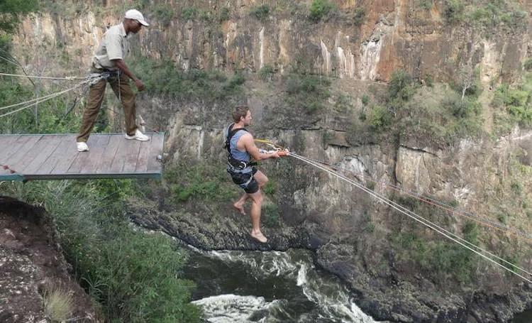 Man just leaping over the platform staring his swing decent on the gorge swing at Victoria Falls