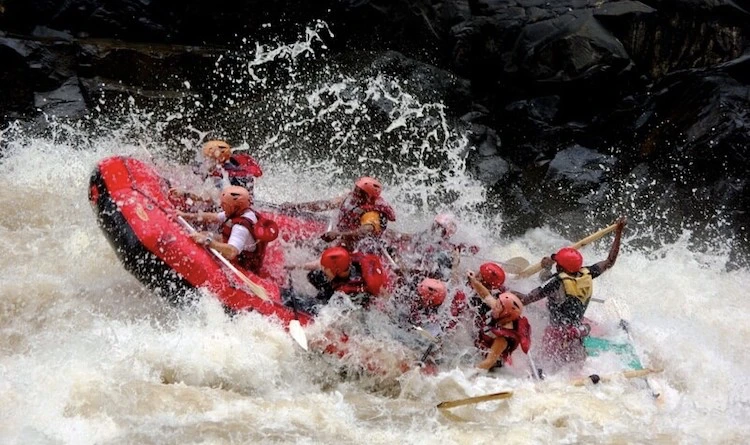 A group white water rafting on the Zambezi River hitting rapids.